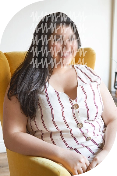 A woman sitting on a sofa, smiling warmly.