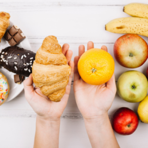 Hands with orange, croissant; healthy vs unhealthy food
